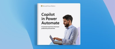 A man in a blue shirt holding a laptop with a white sign that says 'Copilot in Power Automate'.