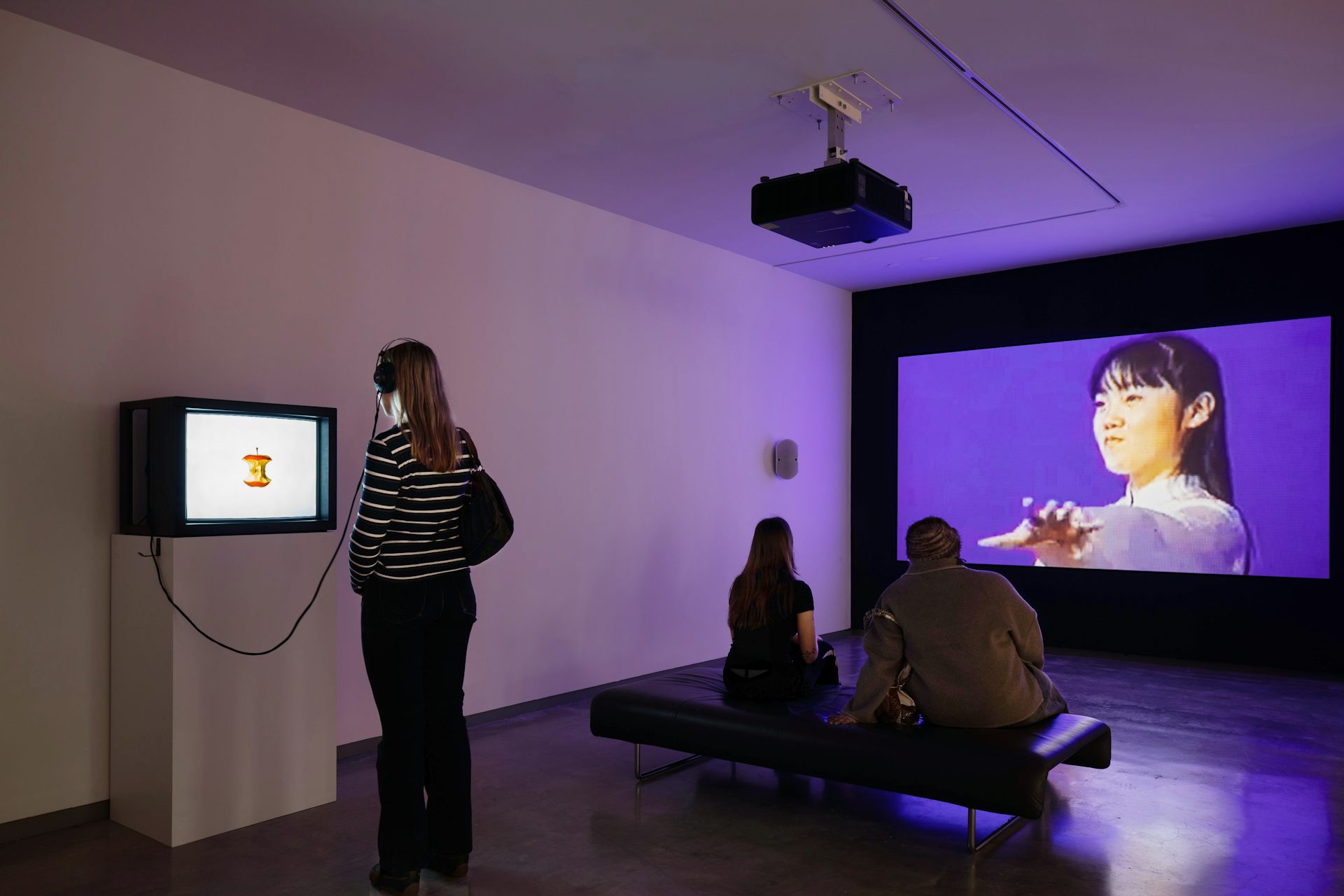Visitors look at various sized screens in a gallery.