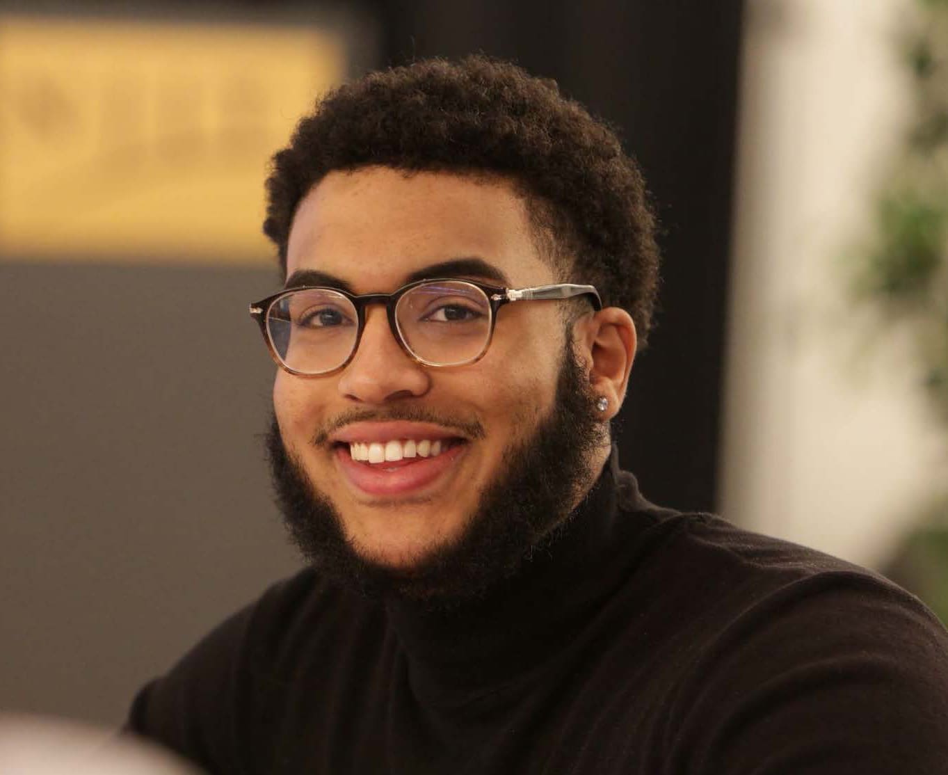 A man with glasses smiling at a table.