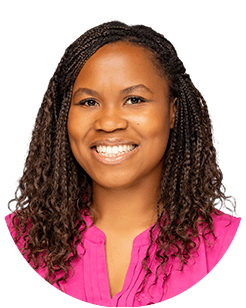 A person with long, curly hair, wearing a pink top, smiles against a white background.
