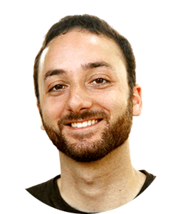 A man with a beard smiling in front of a green background.