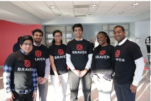 A group of six people wearing Braven t-shirts stand together in a brightly lit room.