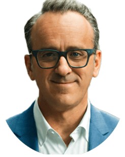 Person with short hair, glasses, and a blue suit, facing the camera with a slight smile.