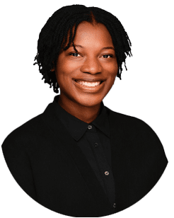 A person with short, twisted hair smiles at the camera, wearing a black collared shirt and black jacket against a plain white background.