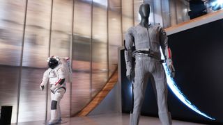 A spacesuit in the background and an undersuit in the foreground on mannequins.