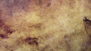 a dense field of glowing stars with cloudy wisps of gas scattered throughout