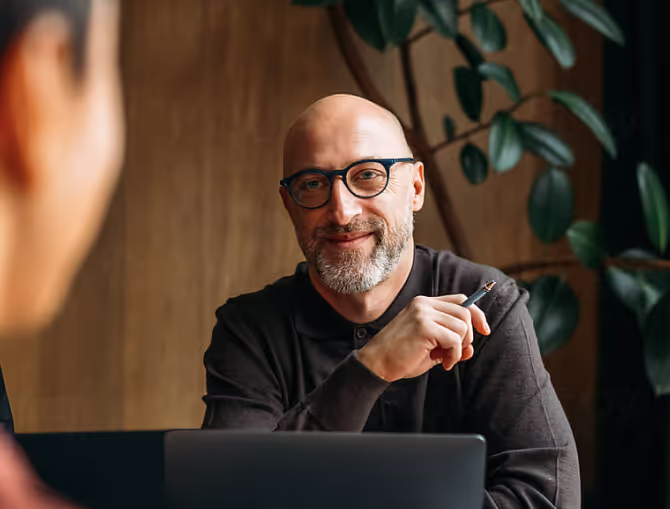 a man with glasses touching his shoulder as he speaks