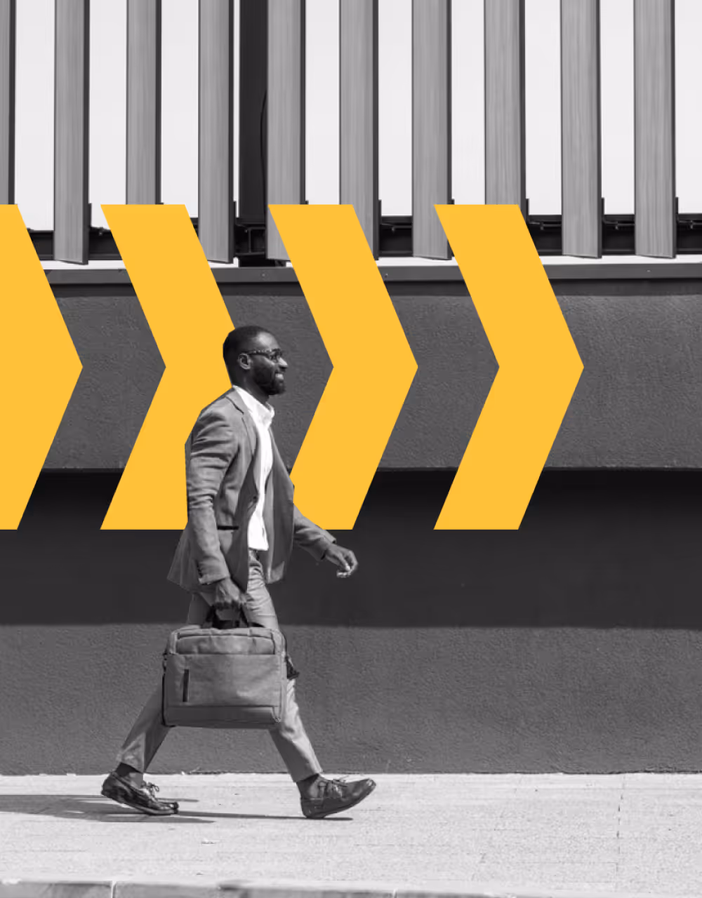 Businessman with briefcase walking confidently in front of a wall with large yellow arrow graphics.