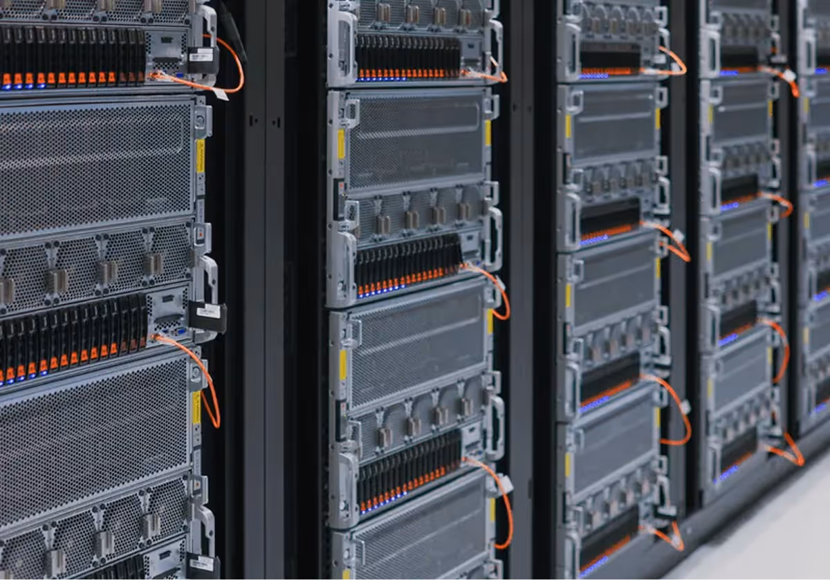 Rows of server racks with connected orange network cables in a data center.