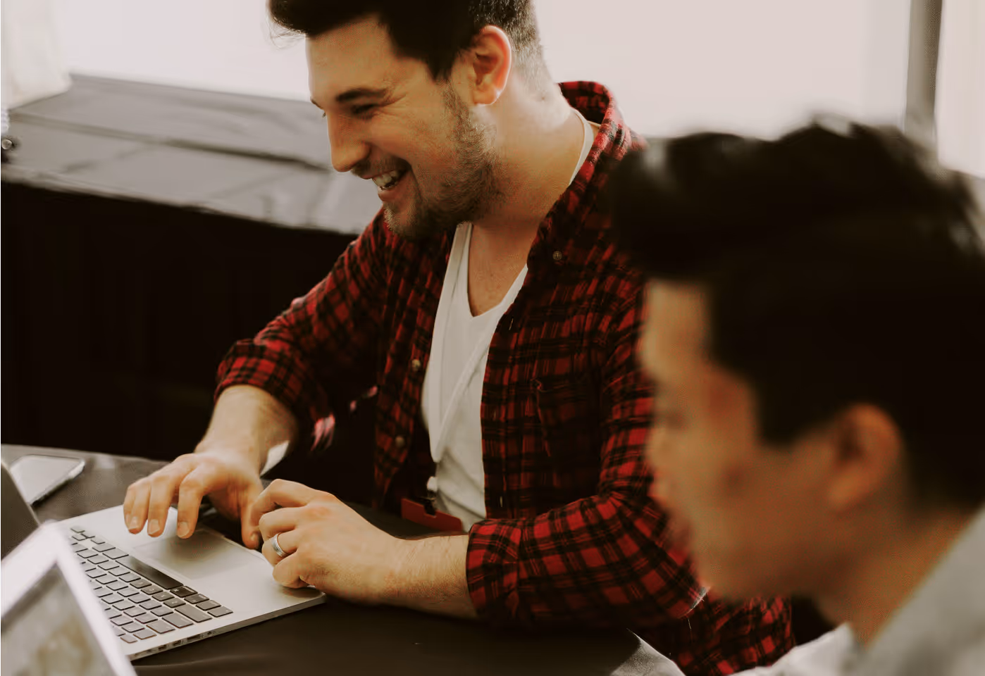 Image of 2 people working side by side looking at a laptop