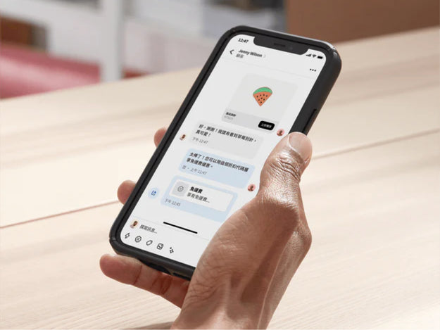 店主在後勤辦公室內用手機透過 Shopify Inbox 與顧客聊天。她在聊天時分享了一組折扣代碼,促成這筆交易。