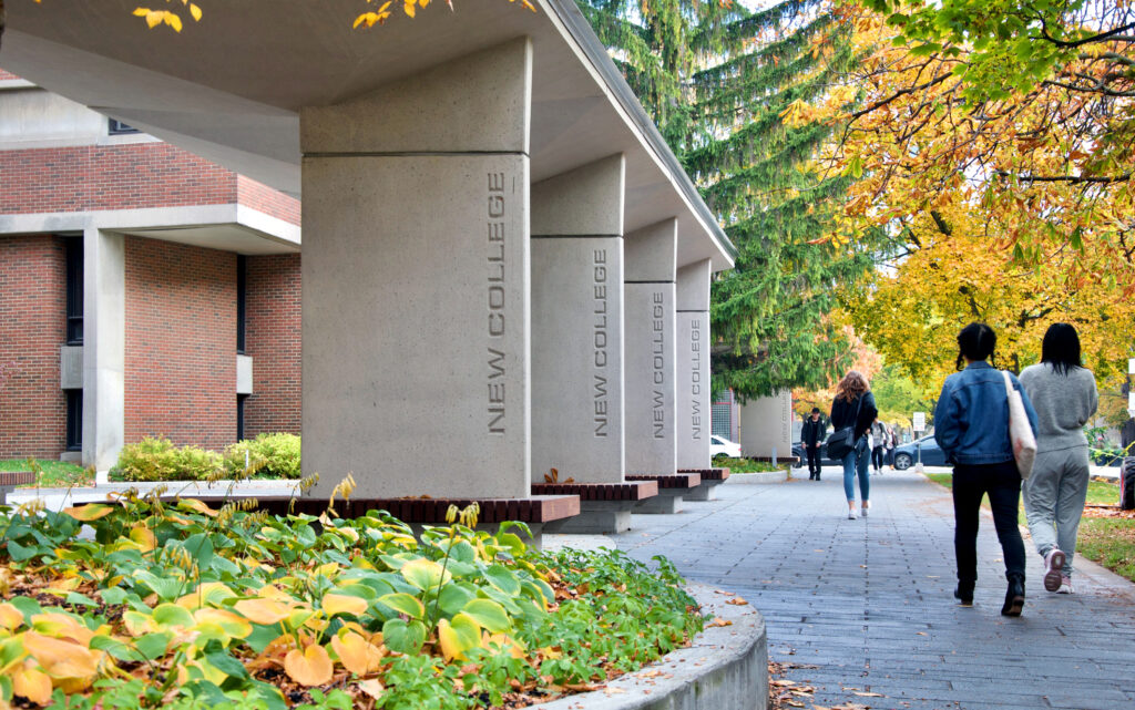 Students walking outside of New College, where the African Studies and Caribbean Studies programs originated, on a fall day.