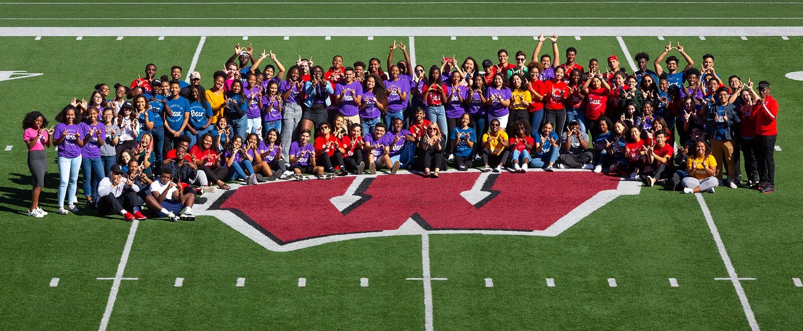 Students and staff in the Posse program at UW–Madison pose for a group photo on the football field in Camp Randall stadium.