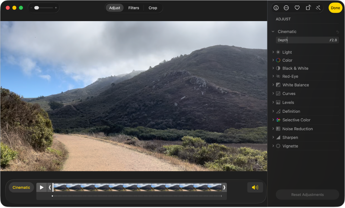 Un video nella vista Modifica con sotto il visore dei fotogrammi. Il pulsante della modalità Cinema e quello di riproduzione sono a sinistra del visore di fotogrammi, mentre il pulsante Audio è a destra. Gli strumenti di regolazione sono visualizzati nel pannello Regola.