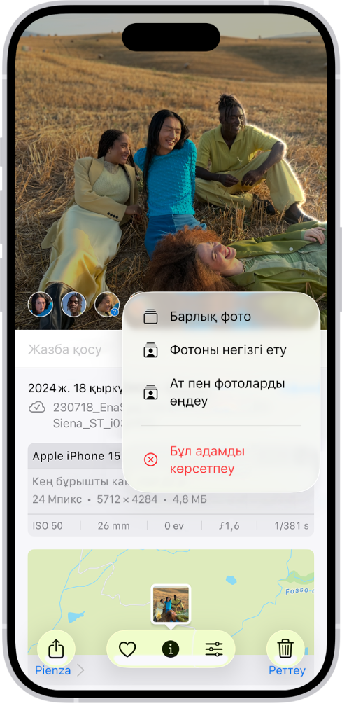 iPhone экранының жоғарғы жартысы «Фотолар» қолданбасындағы ашық фотоны көрсетеді. Фотоның төменгі сол жақ бұрышында фотода пайда болған адамдардың беттері бар. Беттердің біреуінің жанында сұрақ белгісі бар. Опциялар мәзірі жоғарыдан төмен қарай «Барлық фото», «Фотоны негізгі ету», «Ат пен фотоны өңдеу» және «Бұл адамды көрсетпеу» опцияларын қамтиды.
