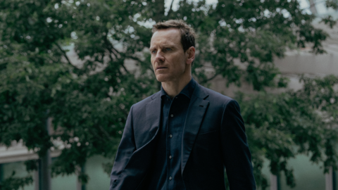 Michael Fassbender as Martian dressed in a black shirt and suit jacket