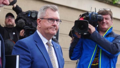 Sir Jeffrey Donaldson walks past a cameraman outside court. He is wearing a blue suit