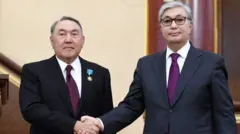 Собиқ раҳбар Назарбаев (чапда) 2022 йилда унинг вориси Тоқаев (ўнгда) томонидан сиёсатдан четлаштирилган эди