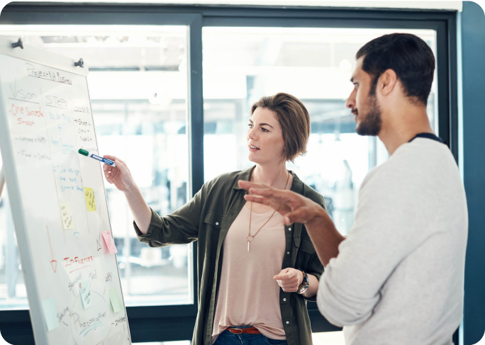 Man and woman in an office looking at a whiteboard