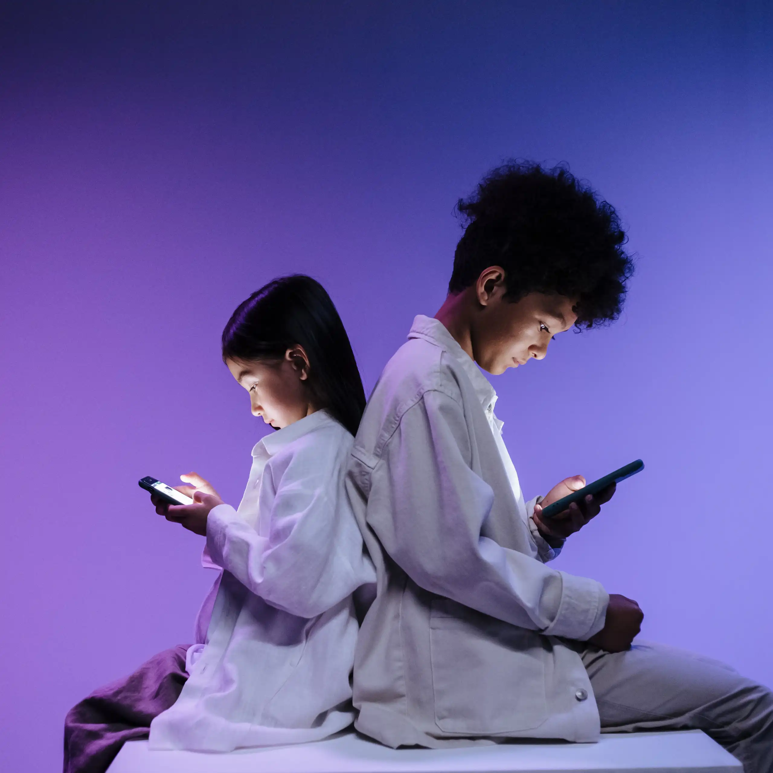 Two children back to back using smartphones on a vibrant purple background.