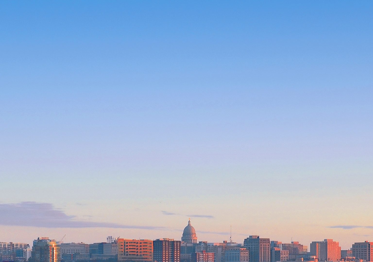 Madison, WI skyline from a distance across a lake at sunrise