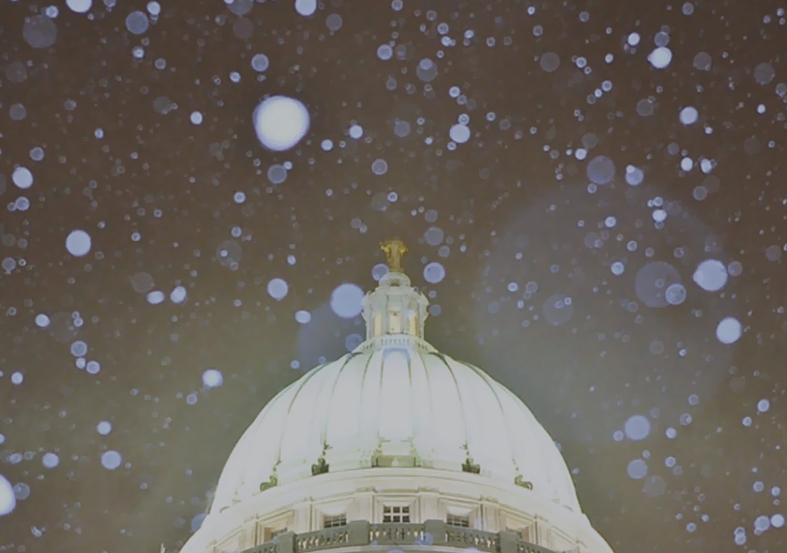 Close-up of Wisconsin State Capitol dome at night with snow falling