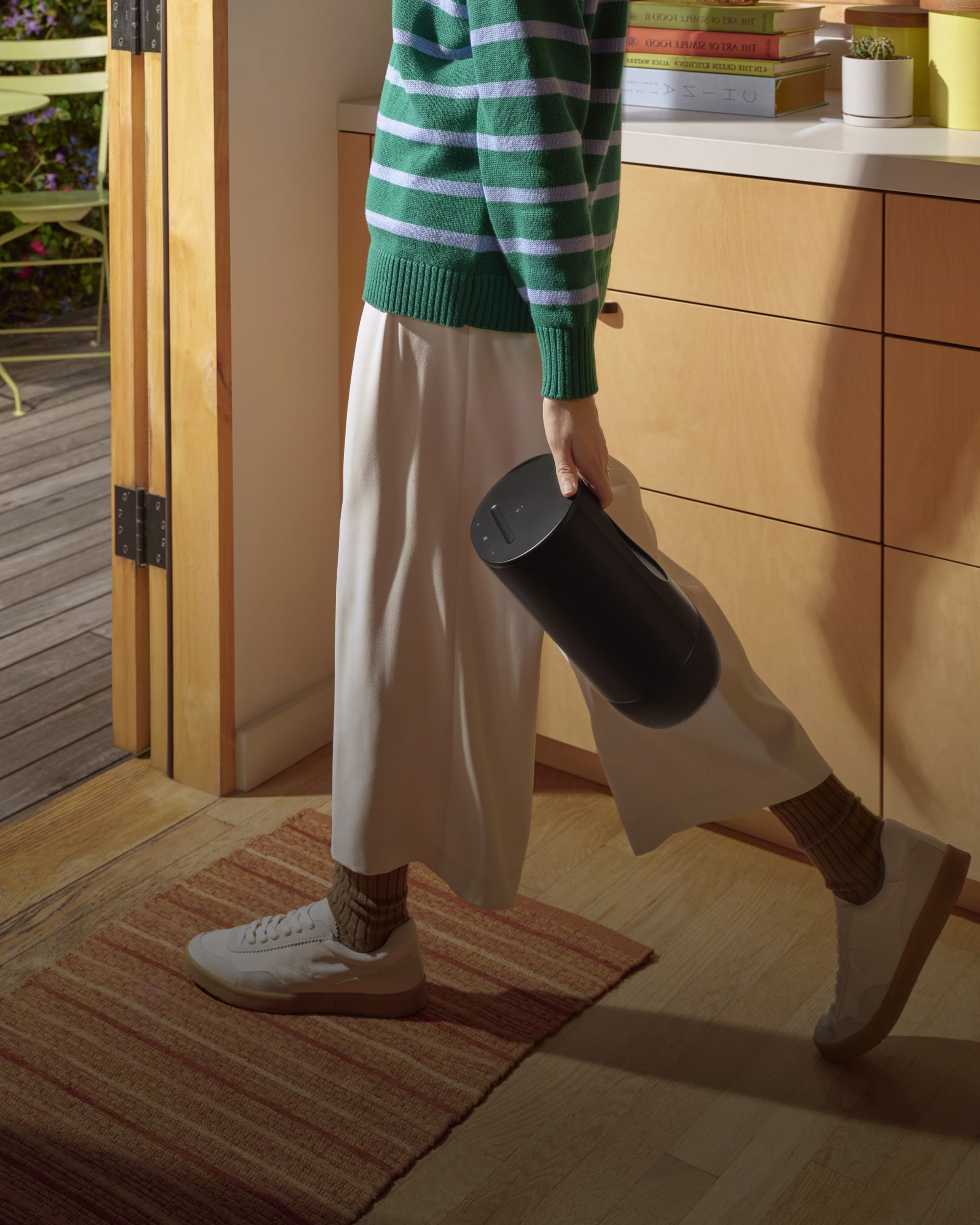 Person holding a black Sonos Move 2 and walking outside