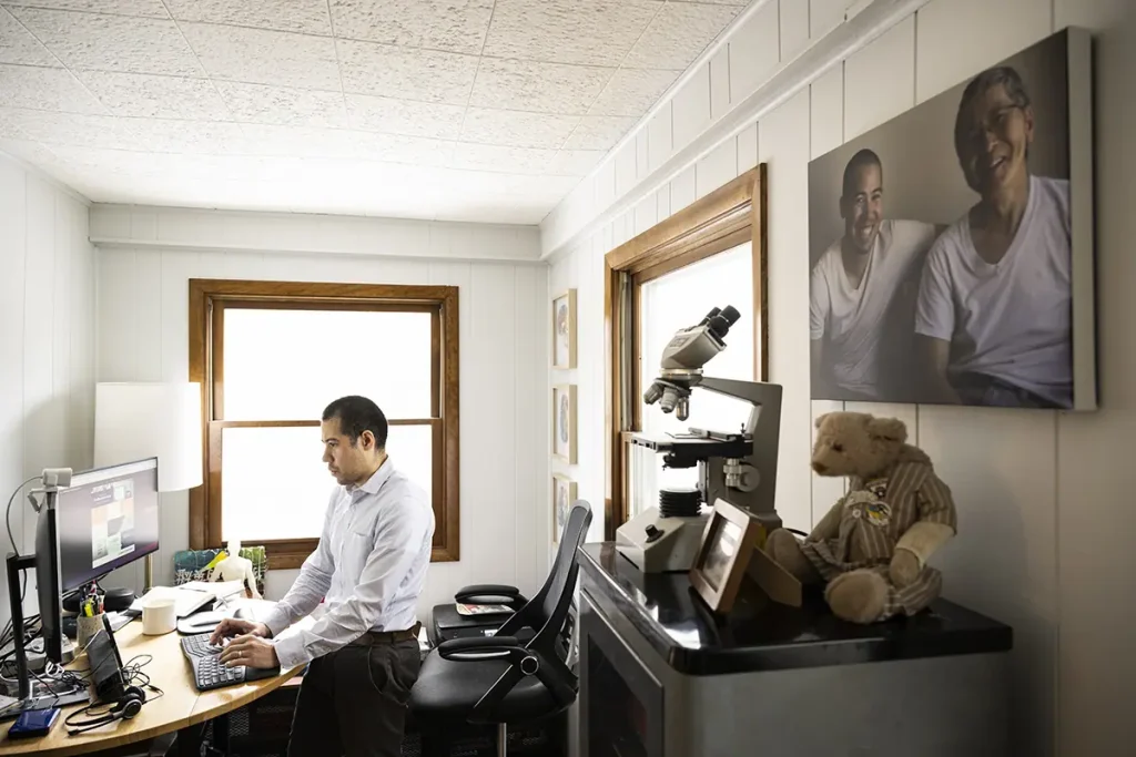 Nate Chin works at a computer in a home office, with keepsakes from his father nearby.