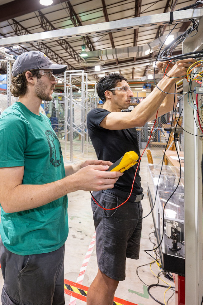 Two people work on a piece of technical equipment.