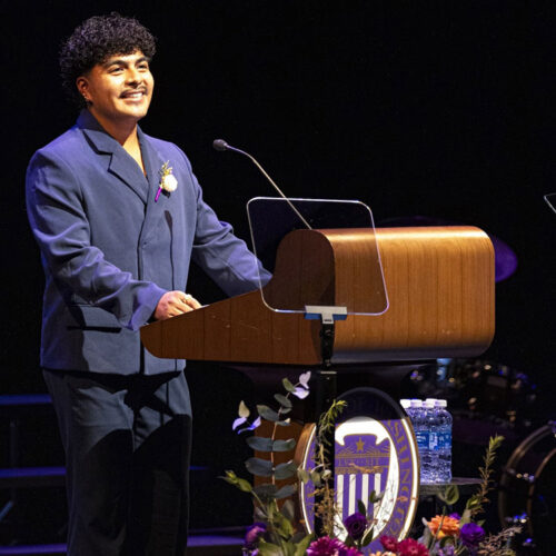 Alex Perez is dressed in a suit, speaking at a podium. The UW official seal is visible.