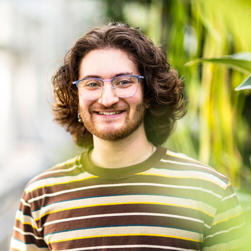 Person wearing glasses and striped shirt in greenhouse