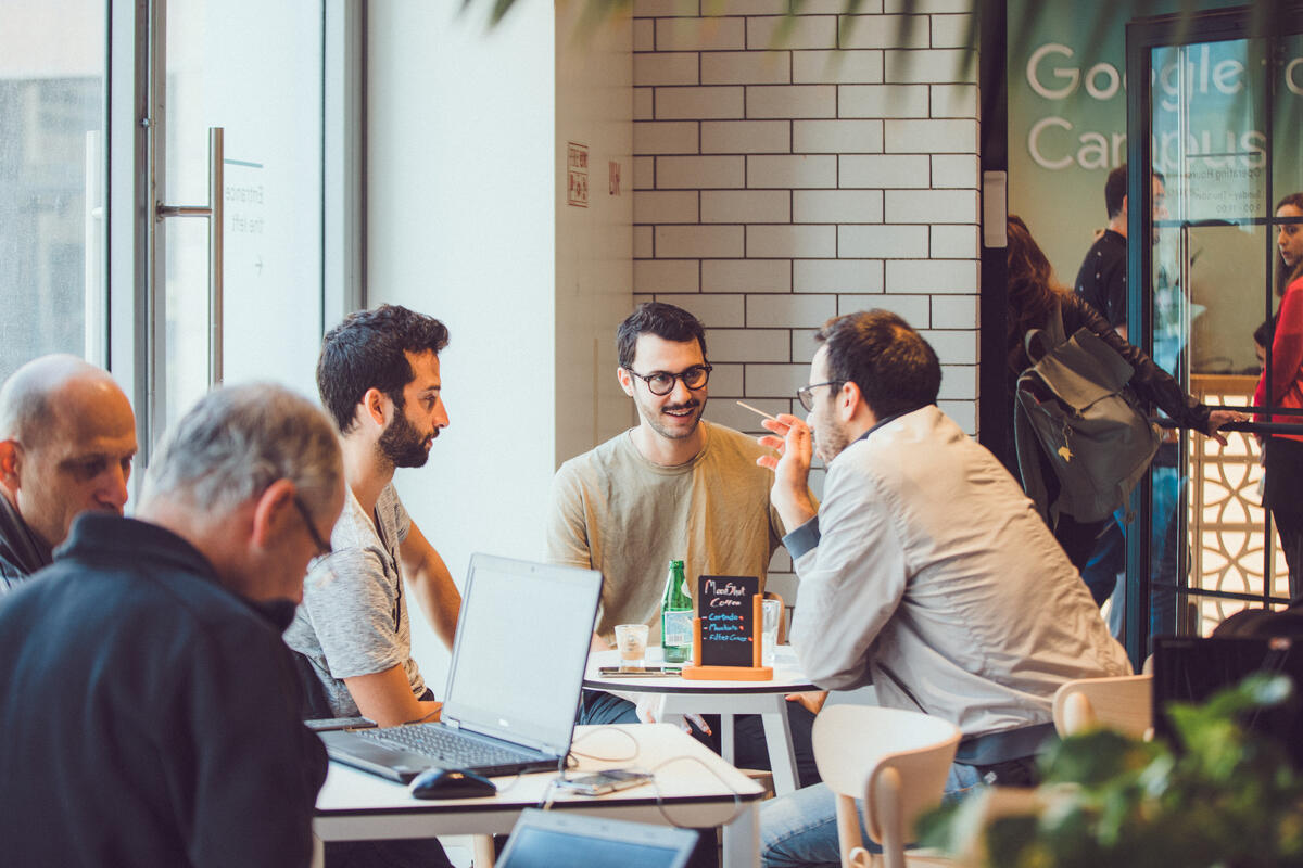 Drei Männer sitzen an einem Tisch und diskutieren